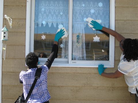 (photo: Sasha Jordan and Tsitsi Gombedza clean a family's window)